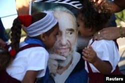 Marian Martin (L) and her sister Chanel (R) kiss a portrait of Cuba's late President Fidel Castro after paying tribute to Castro along with their mother at the Jose Marti Memorial in Revolution Square in Havana, Nov. 29, 2016.