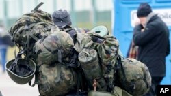 FILE - A man carries combat gear as he leaves Poland to fight in Ukraine, at the border crossing in Medyka, Poland, March 2, 2022. 