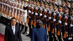 FILE - Chinese Premier Li Keqiang, left, and Solomon Islands Prime Minister Manasseh Sogavare review an honor guard during a welcome ceremony at the Great Hall of the People in Beijing, Oct. 9, 2019.