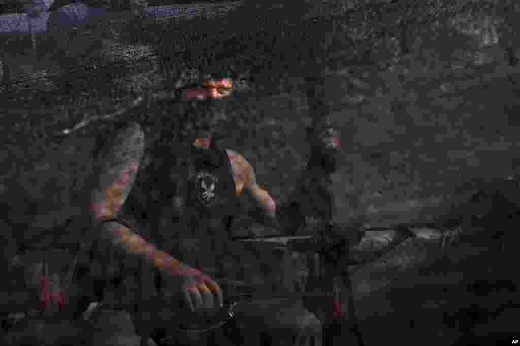 A pro-Russian armed militant sits behind a camouflage net at a checkpoint blocking the major highway which links the Russian city of Rostov-on-Don, and Kharkiv, outside Slovyansk, May 26, 2014.