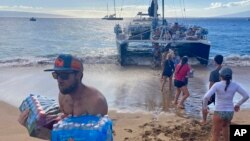 Volunteers who sailed from Maalaea Bay, Maui, form an assembly line on Kaanapali Beach on Aug. 12, 2023, to unload donations. The Maui fire damaged water pipes, resulting in a loss of pressure that likely allowed toxic chemicals along with metals and bacteria into water lines. 