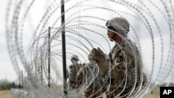 FILE - Members of a U.S Army engineering brigade place concertina wire around an encampment for troops, Department of Defense and U.S. Customs and Border Protection near the U.S.-Mexico international bridge, Nov. 4, 2018, in Donna, Texas.