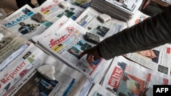 FILE - A man points to a newspaper among the stacks of offerings, in Addis Ababa, Ethiopia, June 24, 2019. 