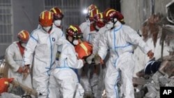 In this photo released by Xinhua News Agency, rescue workers evacuate the 10th person pulled alive from the debris of a self-built residential structure that collapsed in Changsha, China, on May 5, 2022.