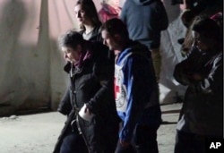 In this photo taken from video, civil evacuees accompanied by Red Cross personnel walk in an area controlled by Russian-backed separatist forces in Bezimenne, about 20 kilometres (12 miles) east of Mariupol, eastern Ukraine, April 30, 2022.