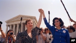 FILE - Norma McCorvey, Jane Roe in the 1973 court case, left, and her attorney Gloria Allred hold hands as they leave the Supreme Court building in Washington, DC., April 26, 1989 after sitting in while the court listened to arguments in a Missouri abort
