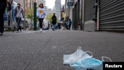 A pair of discarded face masks sit on the side walk in New York City, New York, May 2, 2022. 
