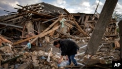 Anna Shevchenko, 35, waters flowers that survived in her home's garden in near Kyiv, May 3, 2022. The house, built by her grandparents, was bombed in March during the Russian invasion of Ukraine.