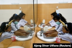 Siswa SD yang memakai masker sedang mencuci tangan usai sekolah, di Jakarta, 9 Maret 2020. Cuci tangan dapat mencegah terjadinya penularan hepatitis. (Foto: REUTERS/Ajeng Dinar Ulfiana)