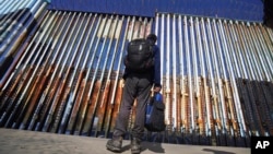 FILE - A migrant waits on the Mexican side of the border after U.S. Customs and Border Protection officers detained a couple of migrants crossing the U.S.-Mexico border on the beach, in Tijuana, Mexico, Jan. 26, 2022.