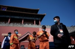 人们在北京紫禁城旁的一个新冠病毒核酸检测点旁排队等候进行检测。（2022年5月1日）