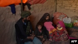 Farishteh (R) and Shokriya (2R), who were recently sold to the families of their future husbands, sit with their parents at the Shamal Darya Internally Displaced People camp in Qala-i-Naw, Badghis Province, Oct. 14, 2021.