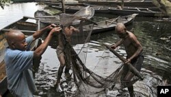 Fishermen sort out their fishing net at the bank of a polluted river in Bidere community in Ogoniland in Nigeria's delta region, August 20, 2011.