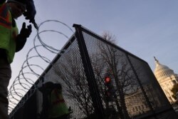 Workers install razor wire atop the unscalable fence surrounding the U.S. Capitol in the wake of the January 6th riot and ahead of the upcoming inauguration in Washington, Jan. 14, 2021.