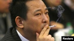 FILE - Liu Han, former chairman of Hanlong Mining, smokes during a conference in Mianyang, Sichuan province.