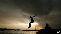 FILE - A boy jumps into the river Ganges during a hot summer day in Prayagraj, India, May 27, 2020. South Asia is especially vulnerable to the impacts of climate change-driven heat waves.