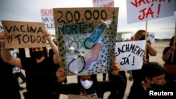Los manifestantes sostienen pancartas durante una protesta en honor a las víctimas de la enfermedad por coronavirus (COVID-19), pidiendo vacunas y contra el presidente brasileño Jair Bolsonaro, frente al Palacio Planalto en Brasilia, el 8 de enero de 2021.
