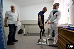 Daviti Suleimanishvili listens to a doctor at an orthopedic clinic in Kyiv on May 25, 2022.