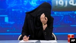 FILE - TV anchor Khatereh Ahmadi bows her head while wearing a face covering as she reads the news on TOLO NEWS, in Kabul, Afghanistan, May 22, 2022, after Taliban rulers required all female TV news anchors in the country to cover their faces while on-air. 