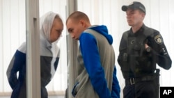 FILE - Russian Sgt. Vadim Shishimarin listens to his translator during a court hearing in Kyiv, Ukraine, May 23, 2022.