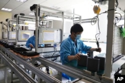 In this photo released by Xinhua News Agency, staff members wearing masks work in an industry park in Qingpu District of Shanghai, east China, May 17, 2022.