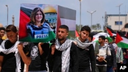FILE - Palestinian students carry a mock coffin as they hold a symbolic funeral for slain Al Jazeera journalist Shireen Abu Akleh, at al-Azhar University in Mughraqa, central Gaza Strip, May 16, 2022. 
