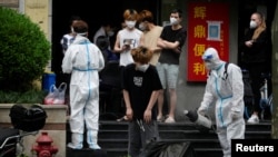 A worker in a protective suit disinfects a person during lockdown, amid the coronavirus disease (COVID-19) outbreak, in Shanghai, China, May 20, 2022.