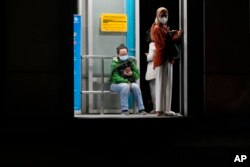 Orang-orang yang memakai masker untuk mencegah penyebaran virus corona menunggu di halte bus di Jakarta. (Foto: AP)