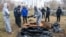 FILE - French forensics investigators, in Ukraine to investigate war crimes amid Russia's invasion, stand next to a mass grave in the town of Bucha, in Kyiv region, Ukraine, April 12, 2022. 