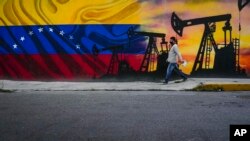 Un hombre pasa frente a un mural alusivo a la industria petrolera en Caracas, Venezuela, el sábado 21 de mayo de 2022.
