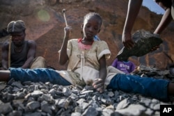 FILE - Irene Wanzila, 10, works breaking rocks with a hammer at the Kayole quarry in Nairobi, Kenya, Sept. 29, 2020, along with her younger brother, older sister and mother.