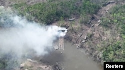 Smoke rises from what appears to be a makeshift bridge across the Siverskyi Donets River, eastern Ukraine, in this handout image uploaded on May 12, 2022. (Ukrainian Airborne Forces Command/Handout via REUTERS)