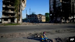 Dječak se igra ispred zgrada uništenih u bombardovanju, u Borođanki, Ukrajina, 24. maja 2022.