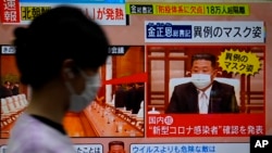 A passerby walks past a screen displaying an image of North Korean leader Kim Jong Un wearing a face mask on a TV news program in Tokyo, May 13, 2022.