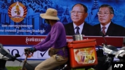 រូបឯកសារ៖ អាជីវករម្នាក់ជិះកង់កាត់រូបបដាតំណាងគណបក្សប្រជាជនកម្ពុជា នៅរាជធានីភ្នំពេញ កាលពីថ្ងៃទី ២៦ ខែកក្កដា ឆ្នាំ ២០១៨។