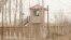 FILE - A security person watches from a guard tower around a detention facility in Yarkent County in northwestern China's Xinjiang Uyghur Autonomous Region, March 21, 2021.
