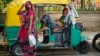 An elderly auto rickshaw driver exhausted from intense heat rests in his vehicle as a woman covering her face walks past, in New Delhi, India, May 19, 2022. In spite of sporadic rains the Indian capital is still facing extreme heat conditions.