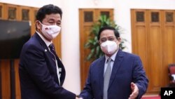 Vietnamese Prime Minister Pham Minh Chinh, right, and Japanese Defense Minister Nobuo Kishi shake hands in Hanoi, Vietnam, Sept. 12, 2021.
