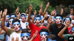 FILE - Young demonstrators flash the three-fingered symbol of resistance during an anti-coup mask strike in Yangon, Myanmar, April 4, 2021.