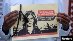 A journalist holds a placard with a picture of Al Jazeera reporter Shireen Abu Akleh, who was killed during an Israeli raid in the occupied West Bank area of Jenin, during a protest in Mogadishu, Somalia, May 13, 2022.