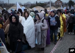 FILE - Refugees wait for transportation after fleeing from Ukraine and arriving at the border crossing in Medyka, Poland, March 7, 2022.