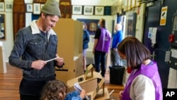 A girl helps her father cast his vote at a polling site in Sydney, Australia, May 21, 2022. 