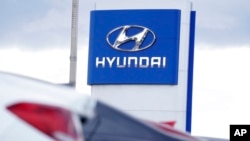 FILE - The company logo hangs over a long row of cars at a Hyundai dealership Dec. 20, 2020, in Centennial, Colo.