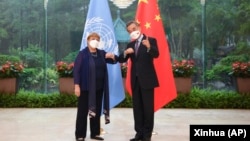 FILE - In this photo released by Xinhua News Agency, Chinese Foreign Minister Wang Yi, right, poses for photo with the United Nations High Commissioner for Human Rights Michelle Bachelet in Guangzhou, in southern China's Guangdong province, May 23, 2022.