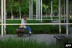 FILE - An elderly man uses his mobile phone next to a cordoned off area amid the COVID-19 pandemic in Beijing, May 27, 2022.