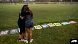 FILE - Two women embrace as they look at signs made by family and friends of people who died from fentanyl-laced pills, including one of their friend, at a makeshift memorial in Santa Monica, California, June 4, 2021.