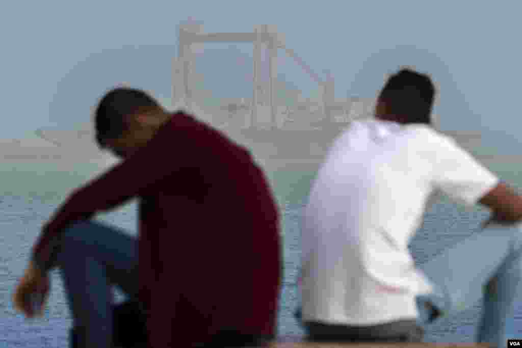 Taking a break during the Eid al-Fitr holidays, two Egyptian men gaze at huge ships heading into the canal from the Red Sea. (Hamada Elrasam/VOA)
