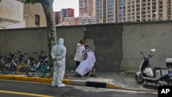A worker in protective gear watches a barber cuts a resident's hair, May 31, 2022, in Shanghai, China. 
