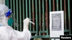 上海一名医务人员从一个固定新冠核酸采样点里给市民进行检测。（2022年5月5日）