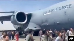 People run alongside a U.S. Air Force C-17 transport plane as it taxis down an airport runway in Kabul, Afghanistan, Aug. 16. 2021. Some were so desperate to escape the Taliban capture of their country that they held onto a jet as it took off and plunged to death. (AP Photo)